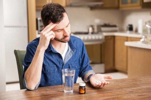 Мужчина пьет таблетки при головной боли